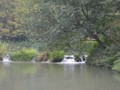 A small water fall flowing between the ponds in the park.