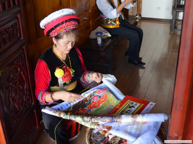 A woman creating an embroidered picture.