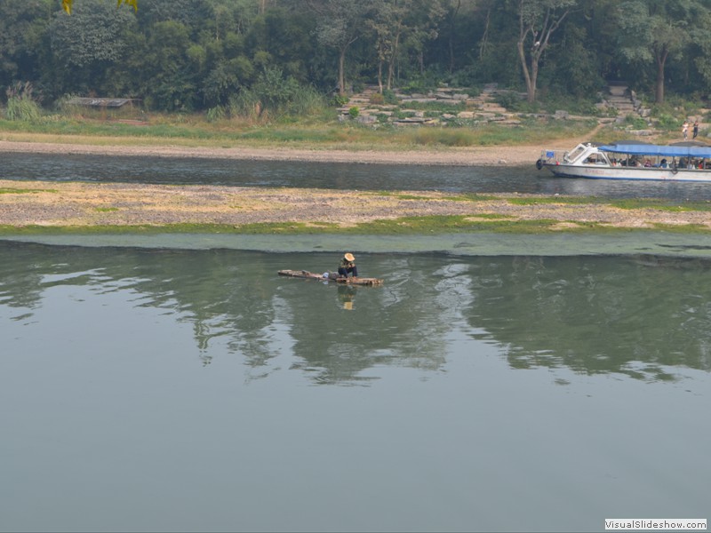 Another fisherman in the river on his bamboo boat