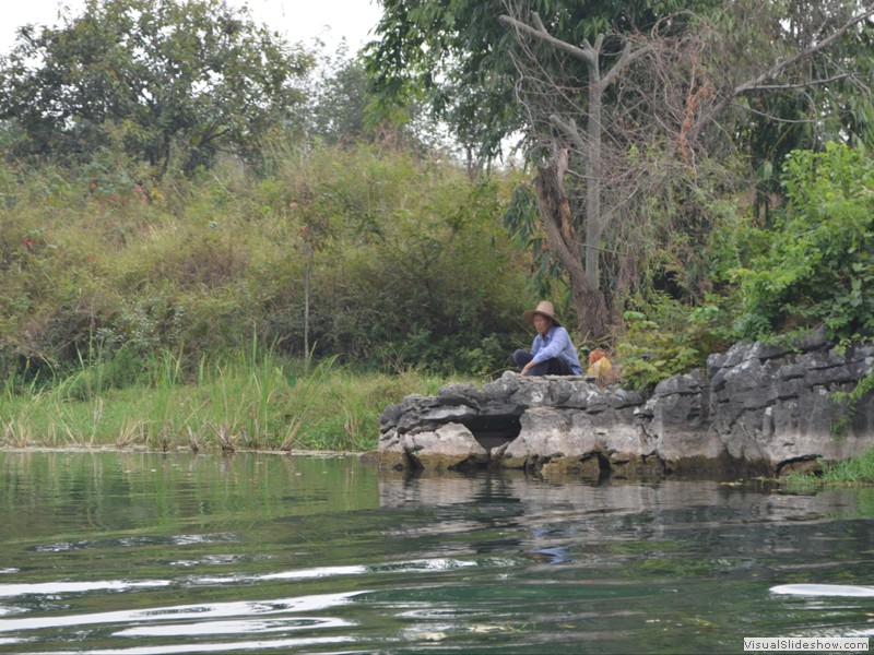 A man fishing along the river.