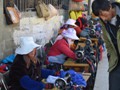 Women fixing garments in a streetside market.